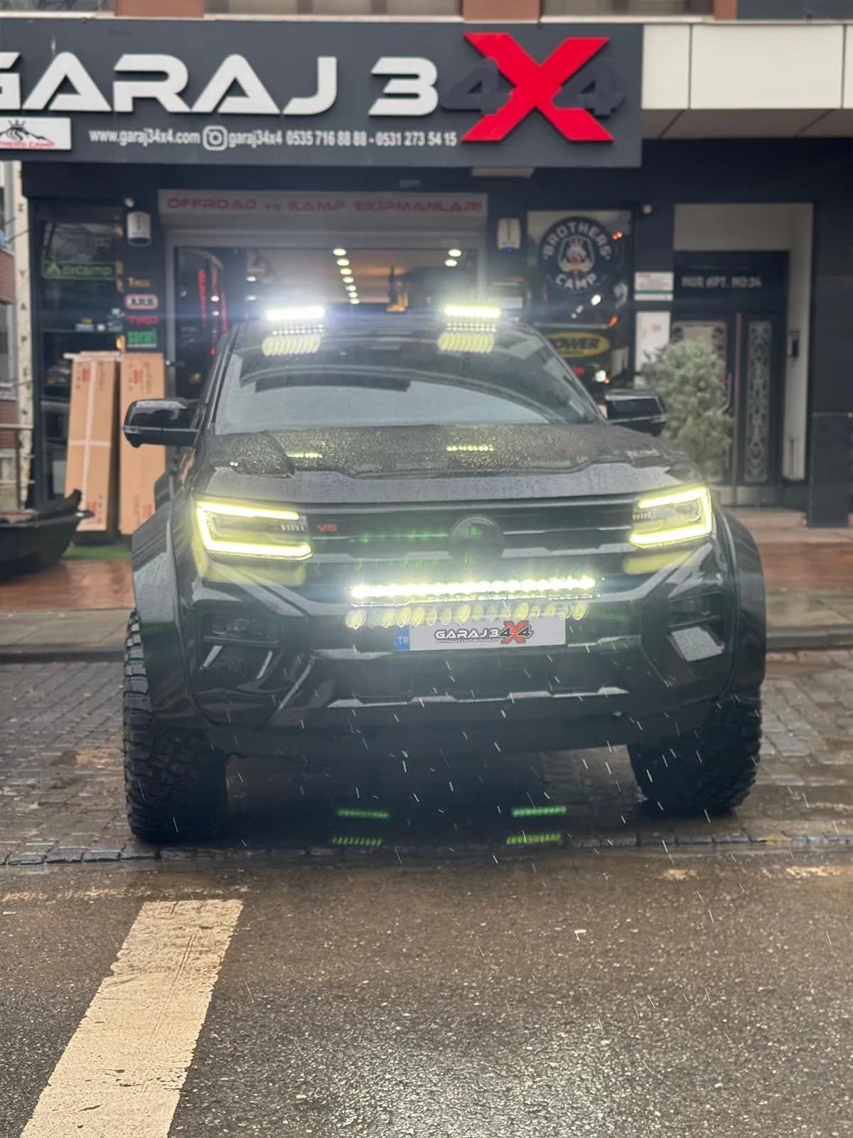 Mağazanın önünde LED bar ve tavan spotları yanan siyah Volkswagen Amarok