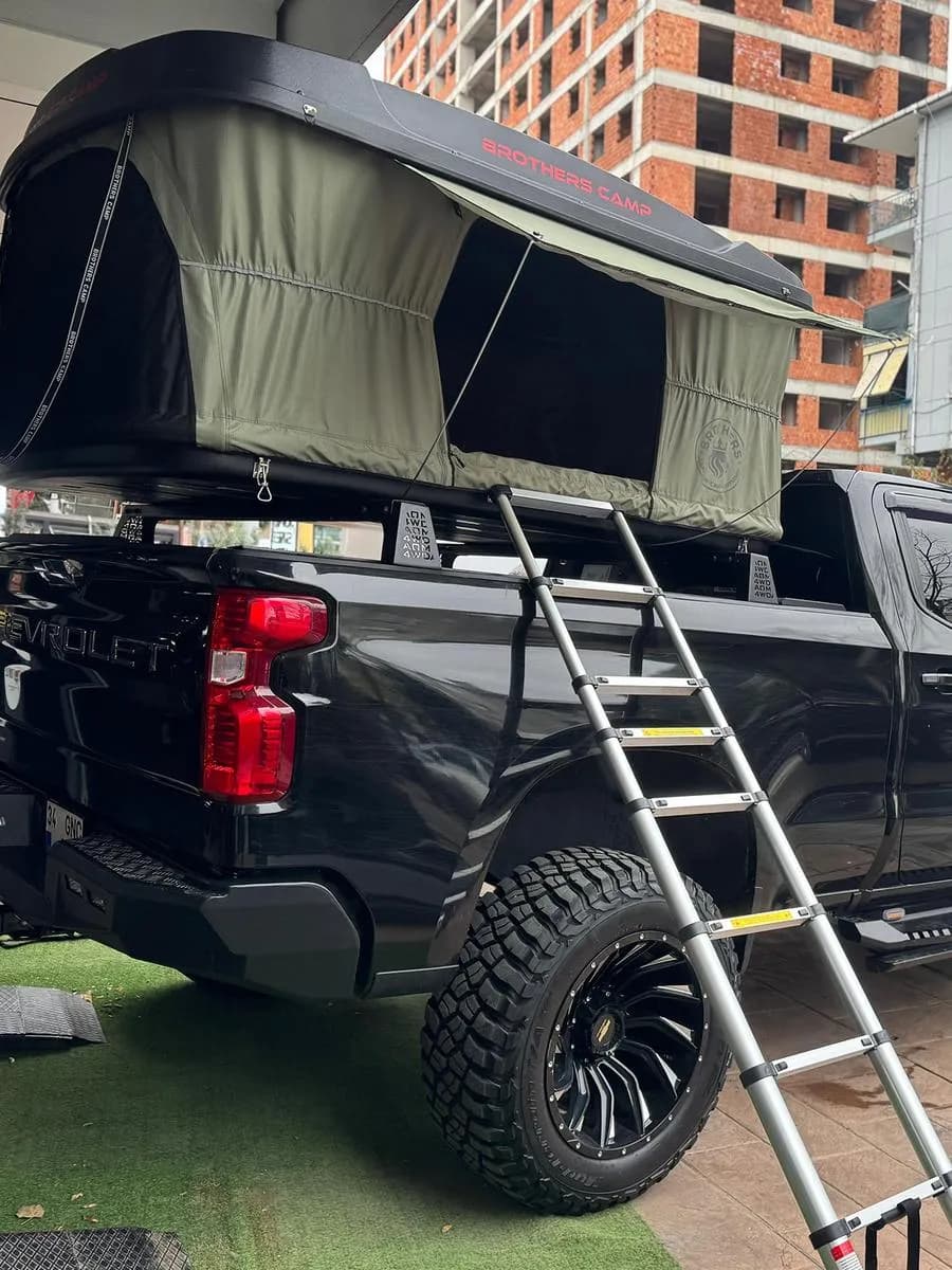 Kasasının üstünde açık araç üstü çadır ve merdiven bulunan siyah pick-up